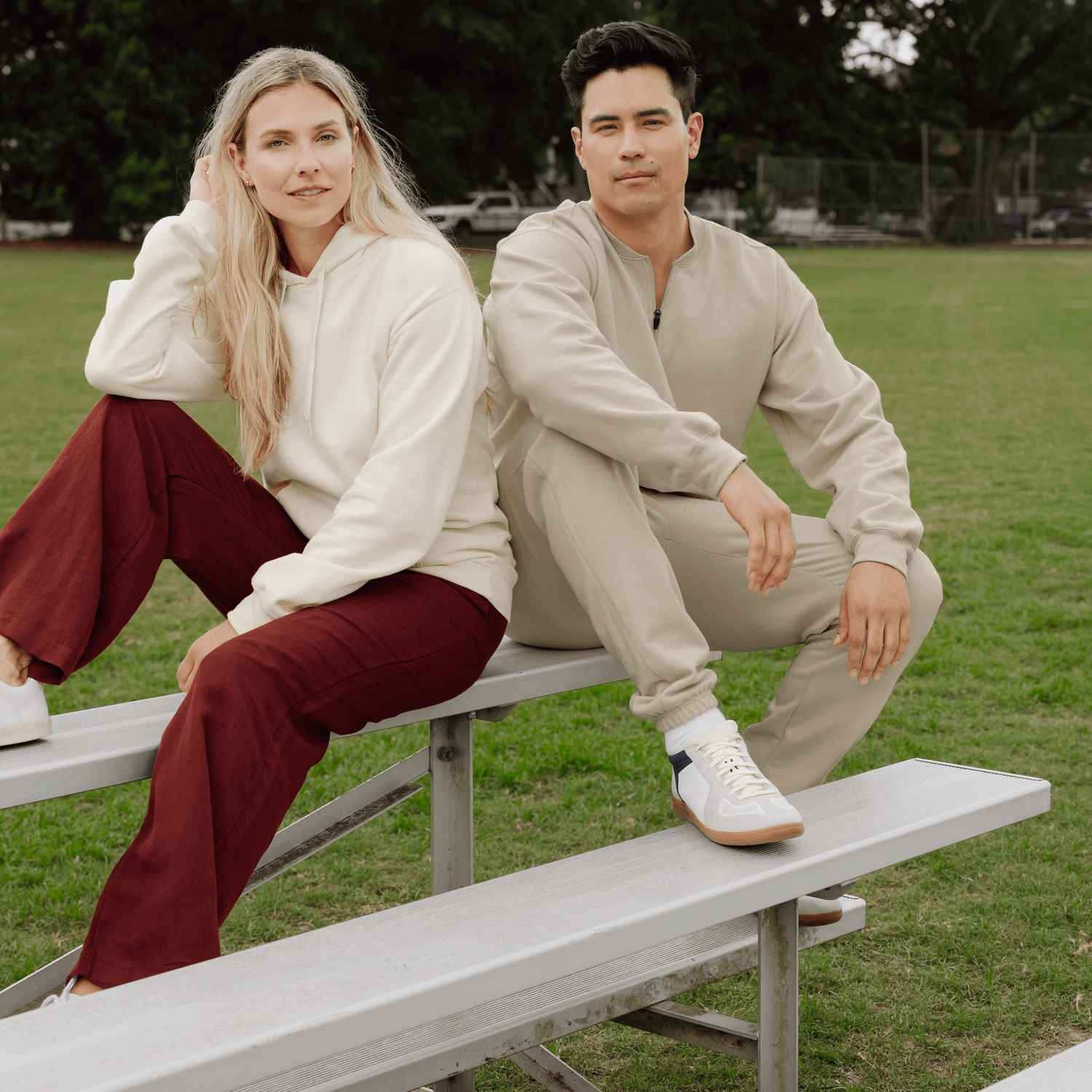 Une femme et un homme portant des t-shirts et des pantalons Gildan sont assis à l'extérieur sur les gradins.