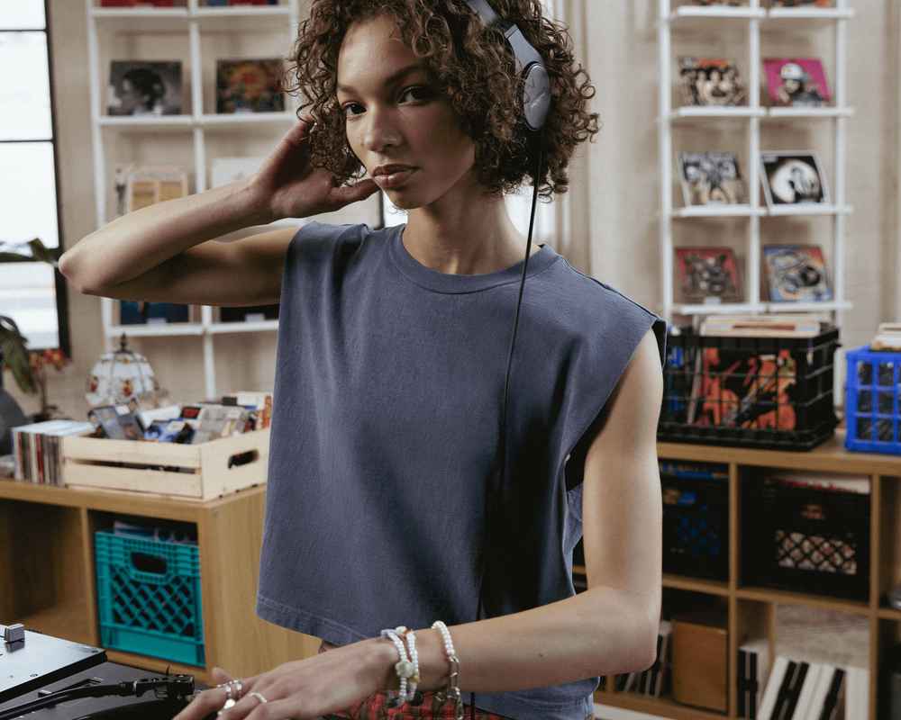 Une femme porte un débardeur gris American Apparel et des écouteurs.