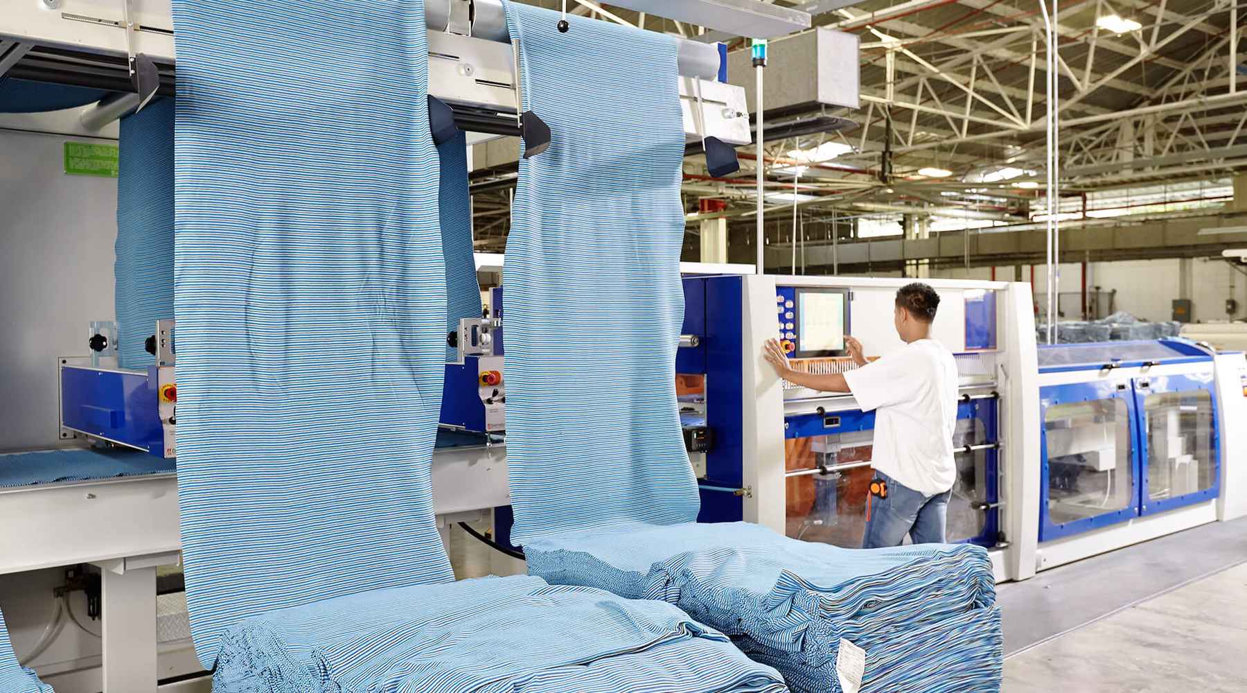 Blue striped fabric is being folded as it exists the drying chambers.