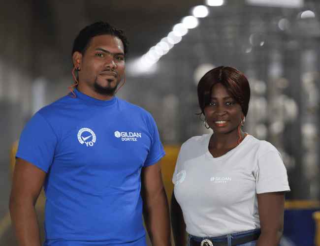 Un homme et des femmes portant des t-shirts Gildan se trouvent dans l'usine de textile en République