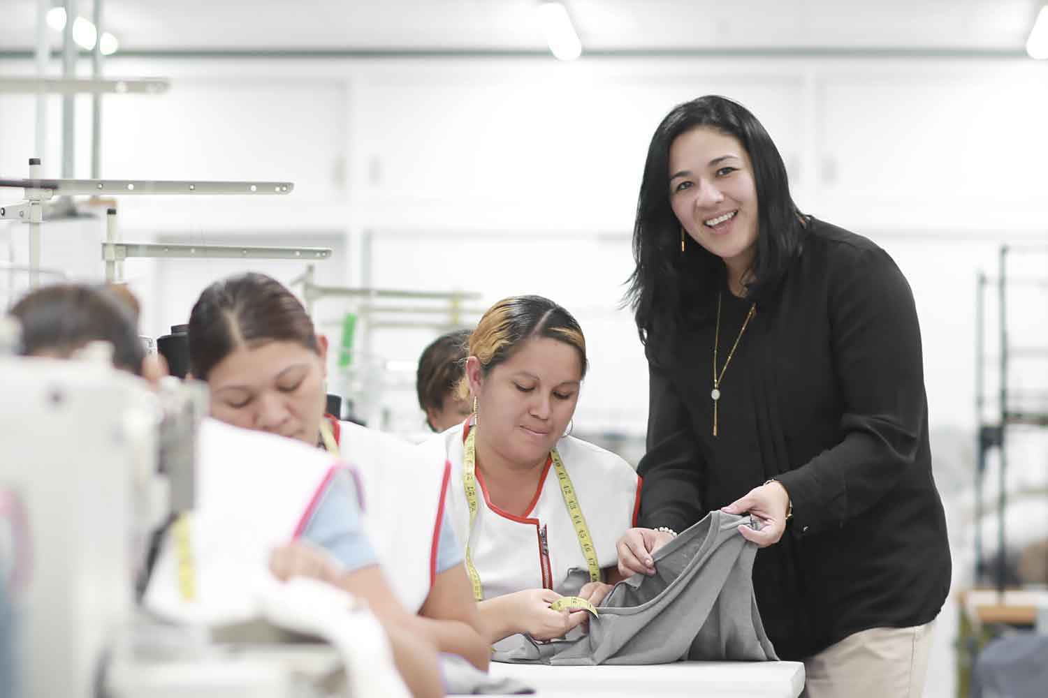 Un manager sourit à la caméra tout en aidant un employé de couture.
