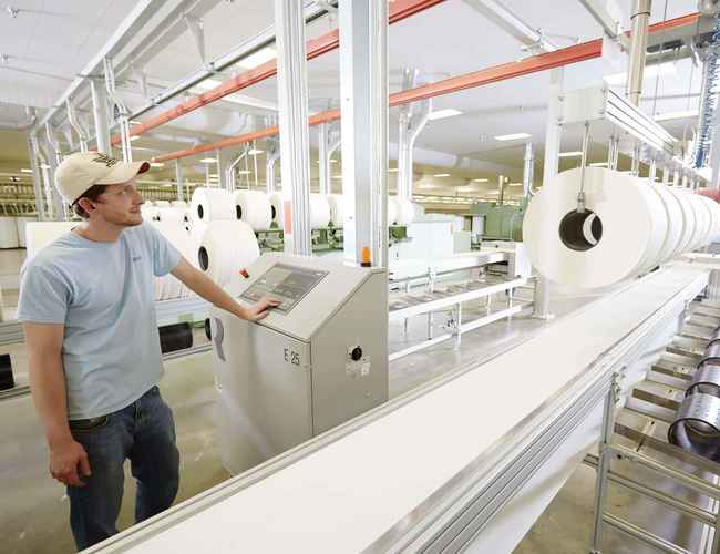 Un employé de filature aux États-Unis fait fonctionner une machine.