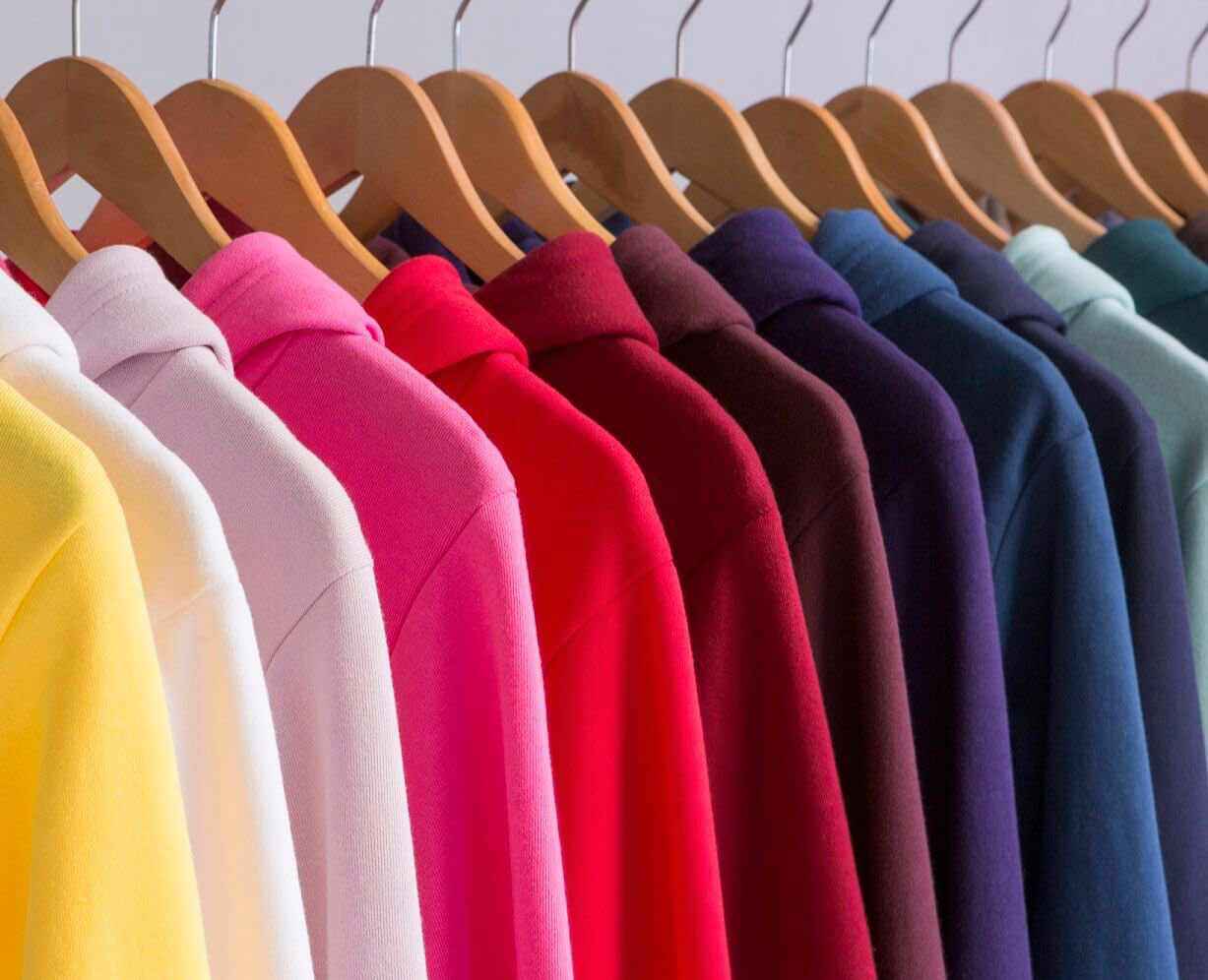 Vibrantly colored American Apparel™ sweaters are hung up on a rack.